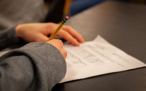  Student completing homework on a piece of paper. 